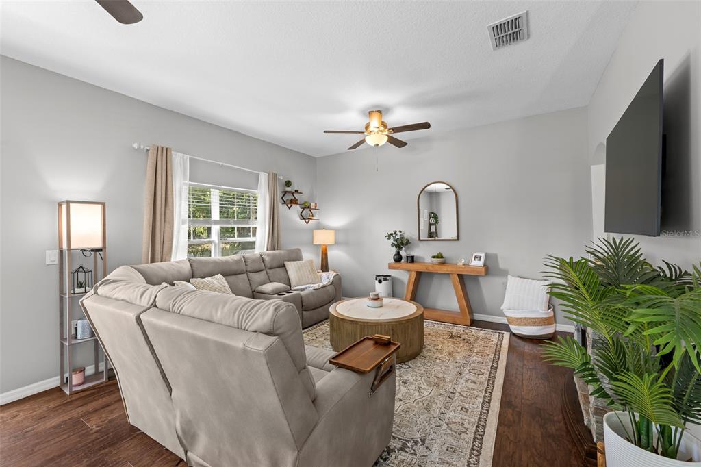 A living room features a grey sectional sofa, a round coffee table, and a wall-mounted television — 8519 BROKEN WILLOW COURT, TAMPA, FL
