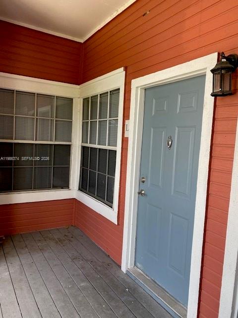 A blue front door and windows are set against orange siding on a wooden porch — 1385 Crystal Way # L, Delray Beach FL 33444, DELRAY BEACH, FL