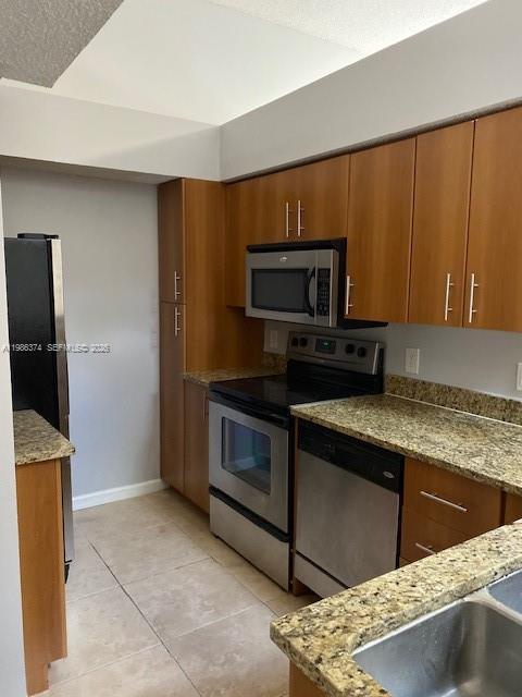 A kitchen features wood cabinets, granite countertops, and stainless steel appliances — 1385 Crystal Way # L, Delray Beach FL 33444, DELRAY BEACH, FL