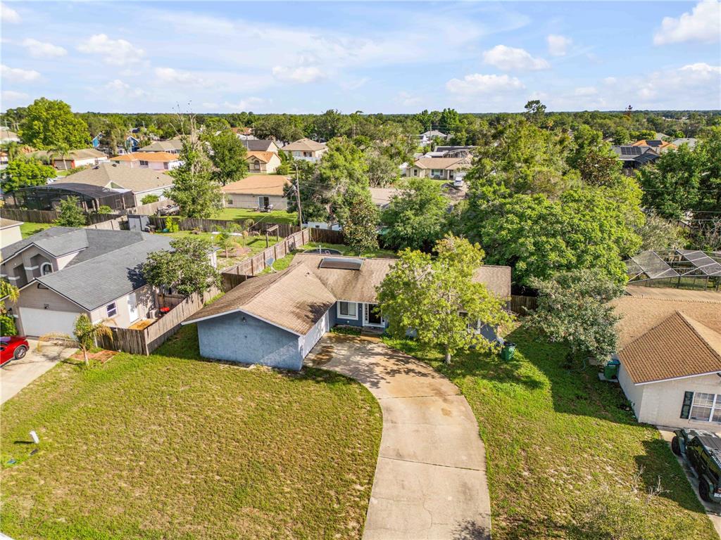 An aerial view shows a single-story house with a concrete driveway and surrounding residential neighborhood — 2550 VESPERO STREET, DELTONA, FL