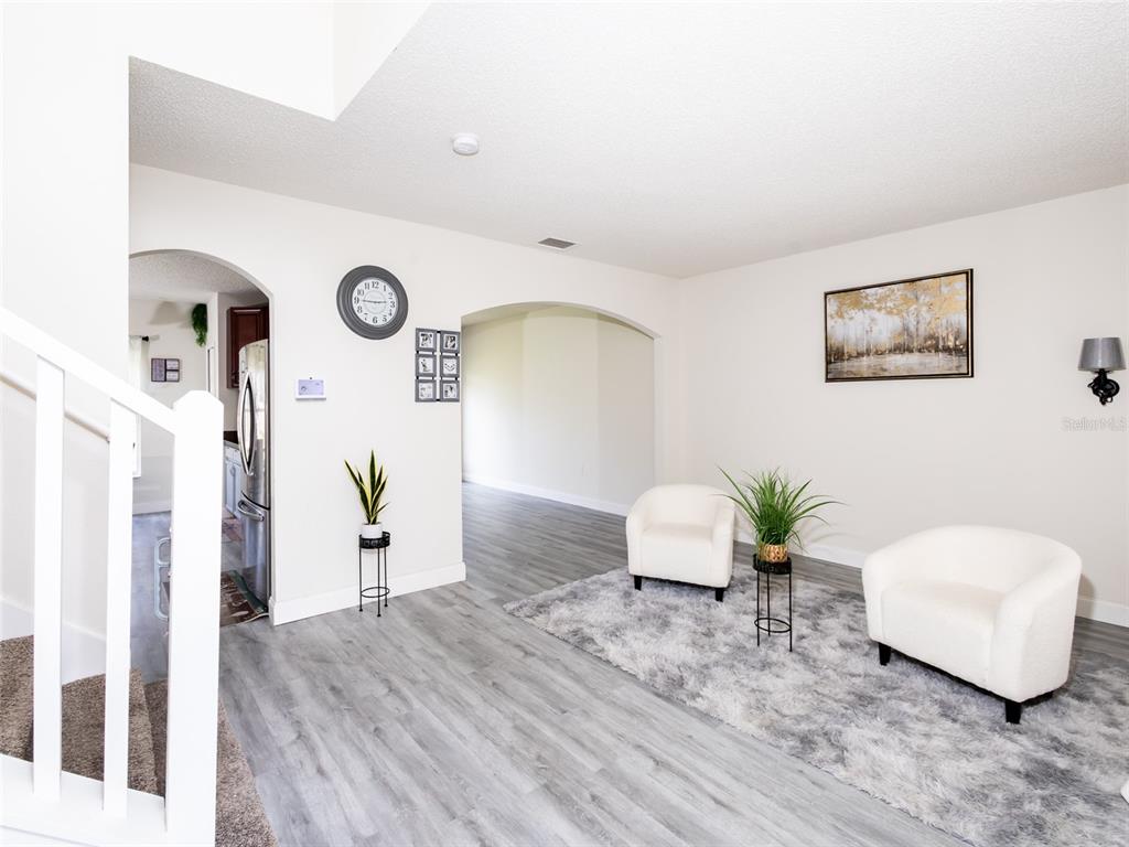 A living area features light gray wood-look flooring, two white armchairs, and arched doorways — 2238 RIO GRANDE CANYON LOOP, POINCIANA, FL