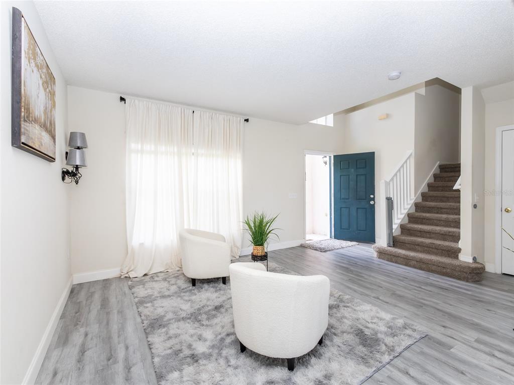 A living room features two white armchairs on a gray rug near a staircase — 2238 RIO GRANDE CANYON LOOP, POINCIANA, FL