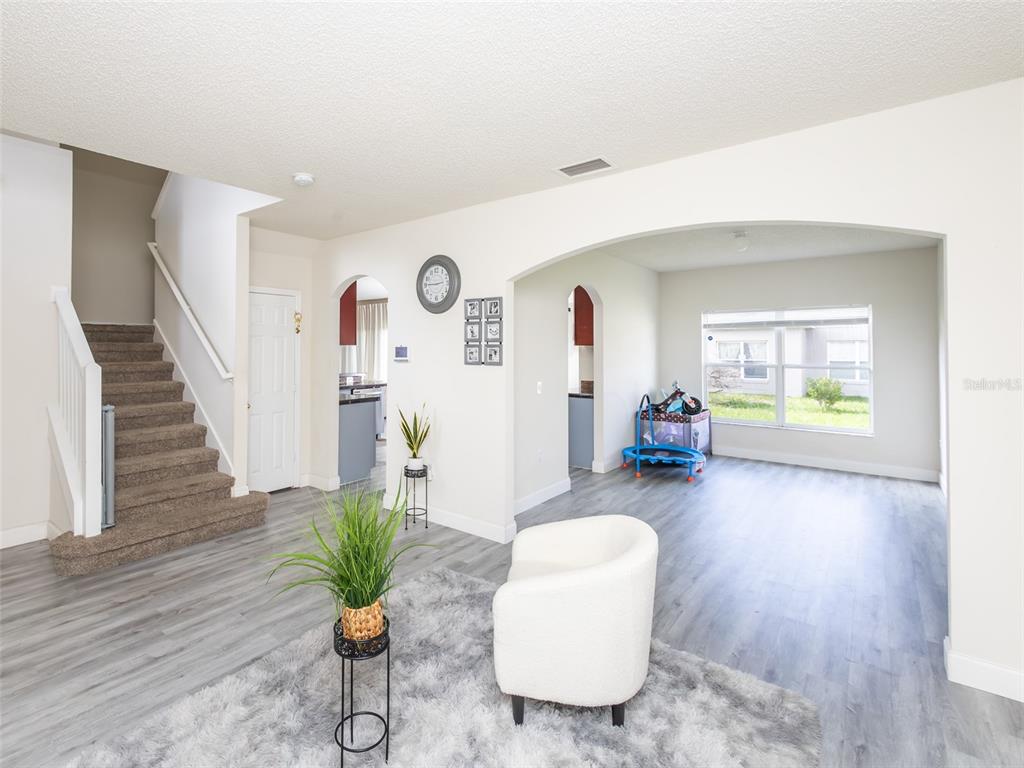 A living area with gray wood-look flooring, a staircase, and an arched opening to another room — 2238 RIO GRANDE CANYON LOOP, POINCIANA, FL