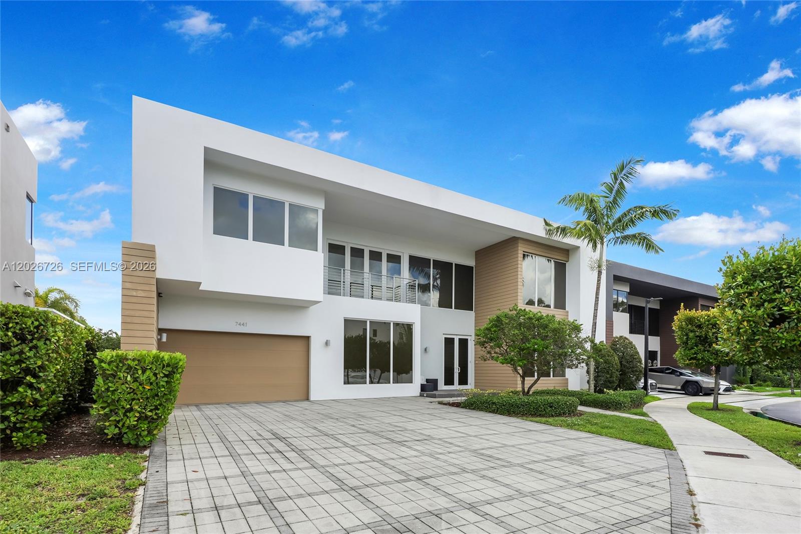 A modern two-story house features a white facade, wood accents, and a paved driveway — 7441 NW 102nd Ct, Doral FL 33178, DORAL, FL