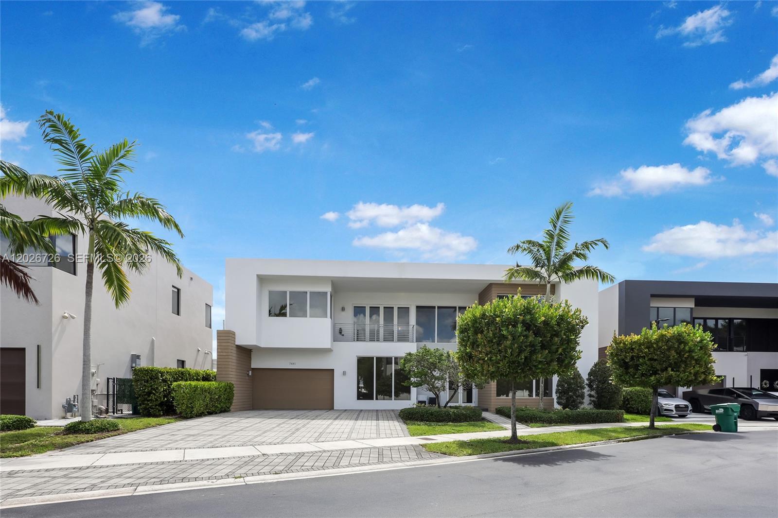 A modern two-story house with a paved driveway, palm trees, and a garage — 7441 NW 102nd Ct, Doral FL 33178, DORAL, FL