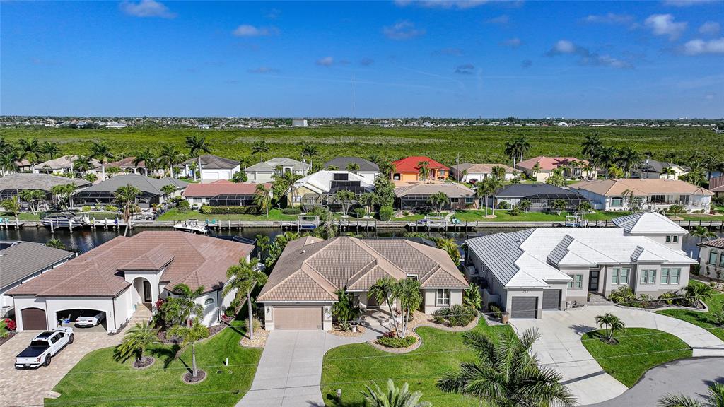 An aerial view shows several suburban houses with tiled roofs and driveways along a canal — 718 ANTALYA COURT, PUNTA GORDA, FL