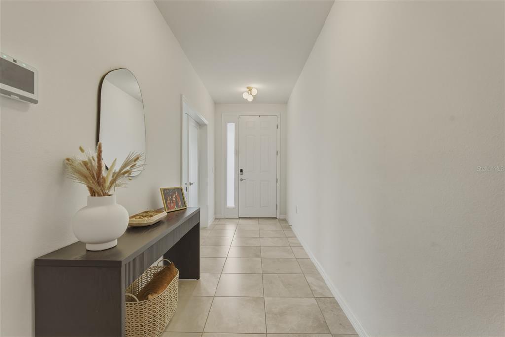 A bright entryway features light tile flooring, a dark console table, and a white door — 17664 NW 173RD ROAD, ALACHUA, FL