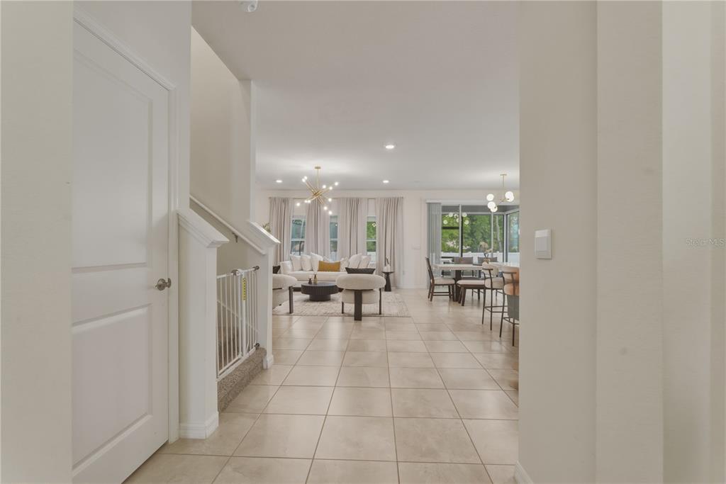 A view from a hallway into an open-concept living room and dining area with tile floors — 17664 NW 173RD ROAD, ALACHUA, FL