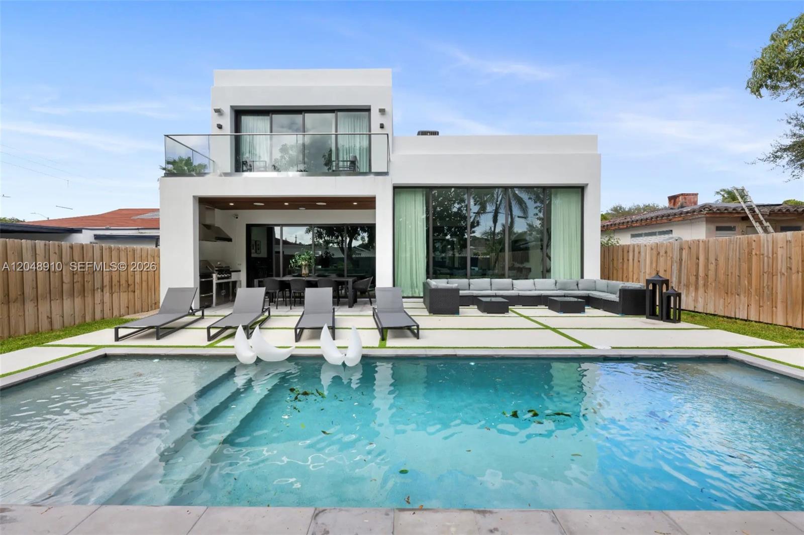 A modern two-story house features a swimming pool, patio furniture, and a wooden fence — 80 NW 45th St, Miami FL 33127, MIAMI, FL