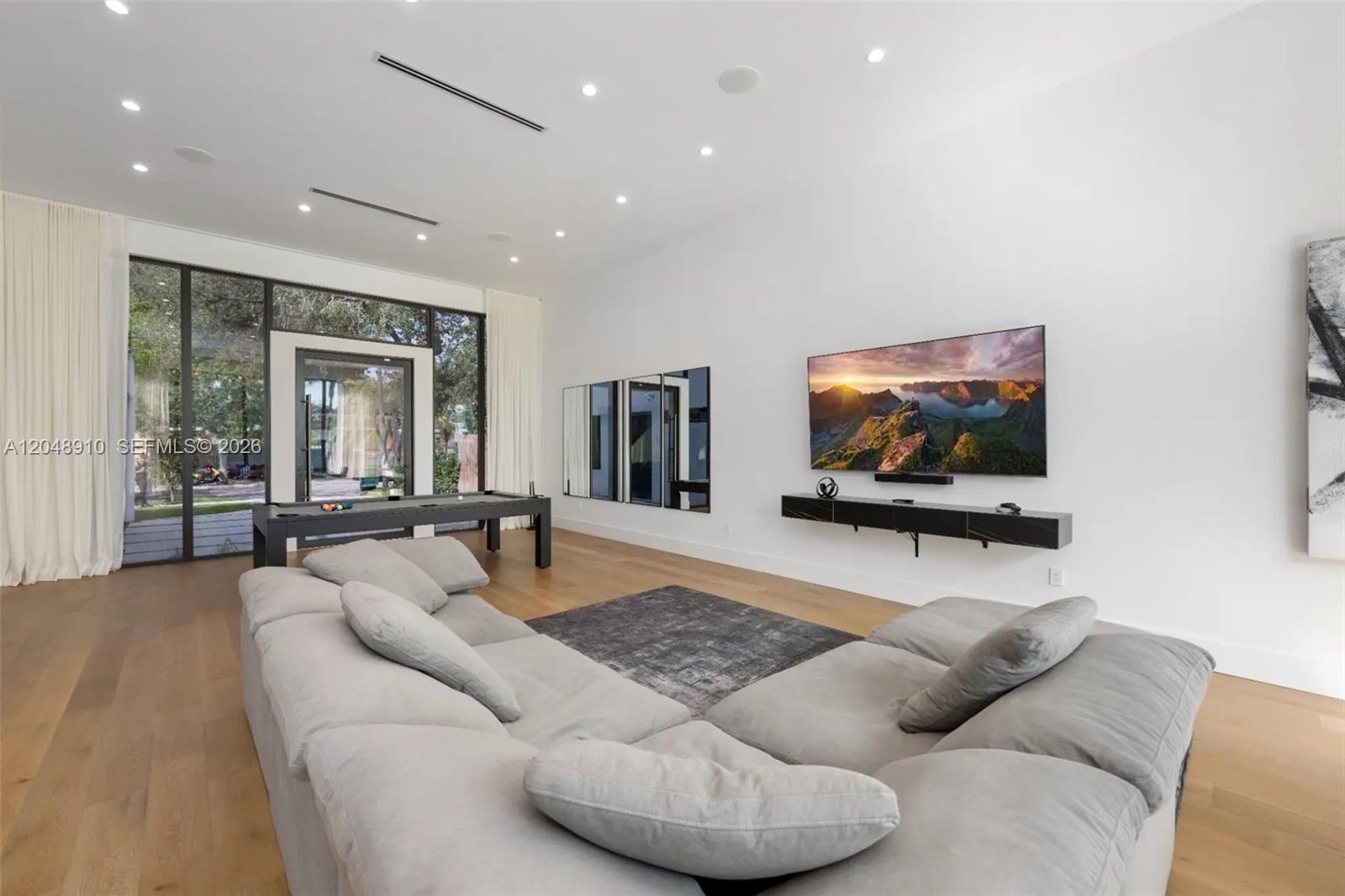 A modern living room features a large gray sectional, a pool table, and a wall-mounted television — 80 NW 45th St, Miami FL 33127, MIAMI, FL