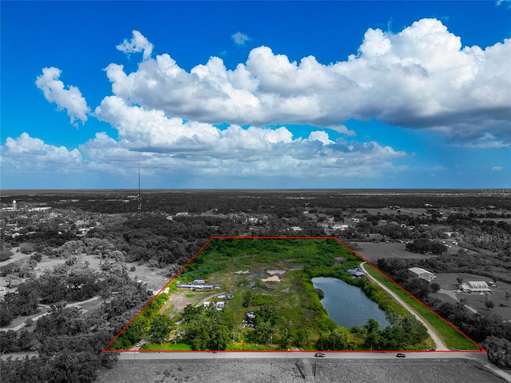 An aerial view shows a rectangular plot of land outlined in red featuring a pond — 301 EAST ROAD, SARASOTA, FL
