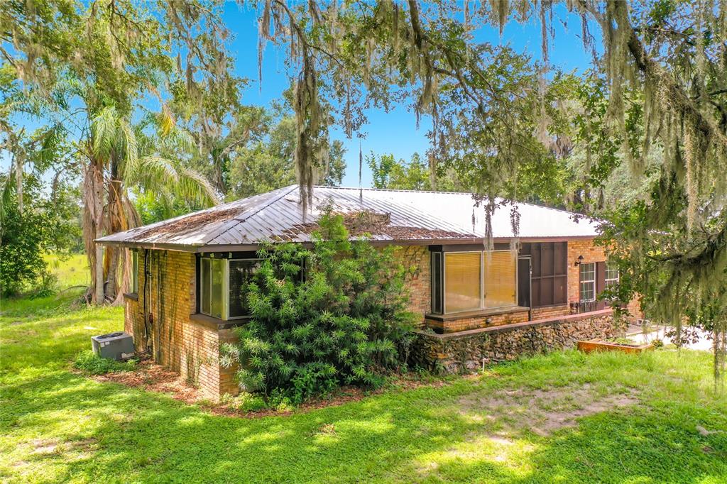 A single-story brick house with a metal roof surrounded by trees with hanging moss — 2736 EMPIRE CHURCH ROAD, GROVELAND, FL