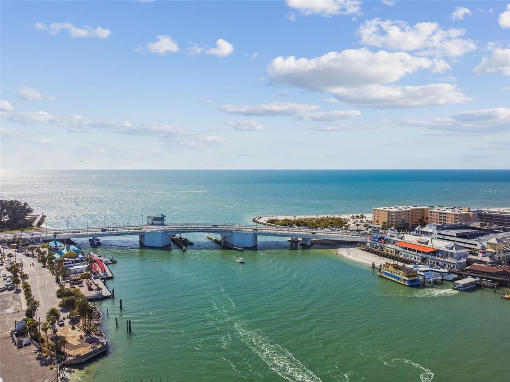 An aerial view shows a bridge crossing a waterway near a beach and buildings — 12000 GULF BOULEVARD UNIT 309N, TREASURE ISLAND, FL