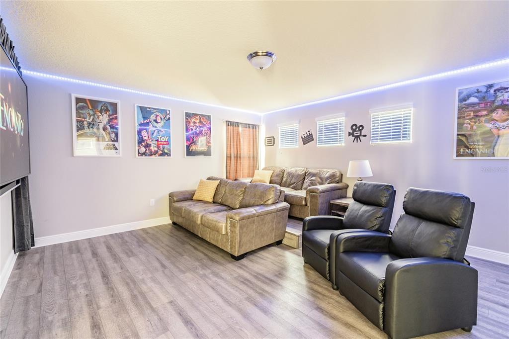 A home theater room features tiered seating, movie posters, and blue LED ceiling lighting — 5352 OAKBOURNE AVENUE, DAVENPORT, FL