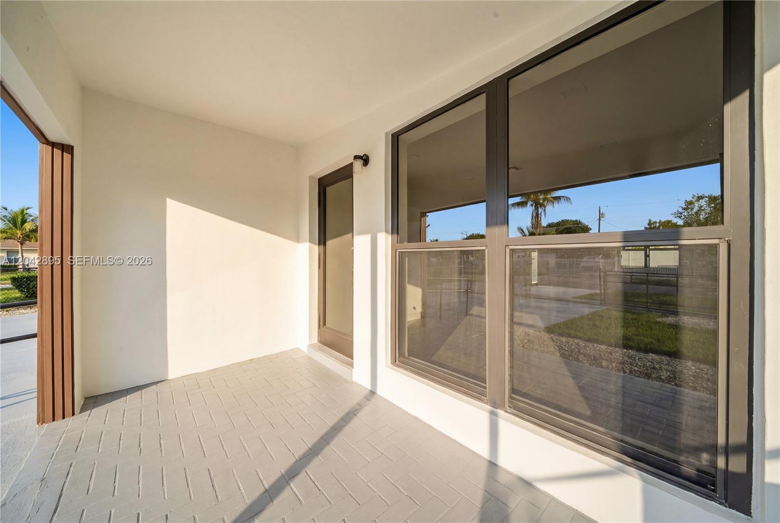 A covered patio features gray herringbone tile flooring, a glass door, and large windows — 12471 SW 190th Ter, Miami FL 33177, MIAMI, FL