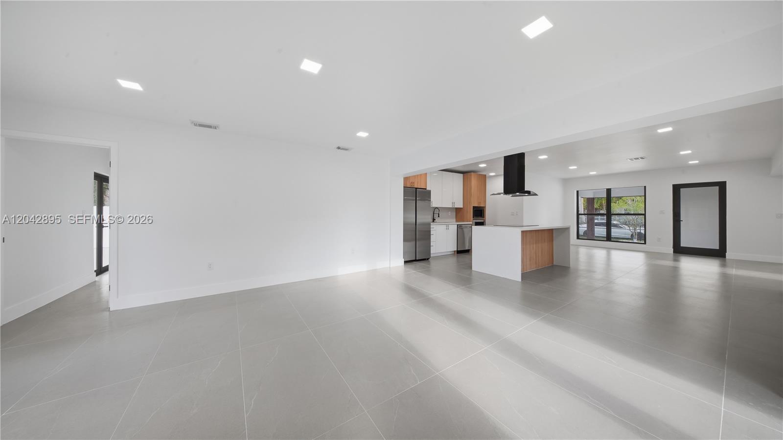 A modern, open-concept living area features large gray floor tiles and a kitchen with an island — 12471 SW 190th Ter, Miami FL 33177, MIAMI, FL
