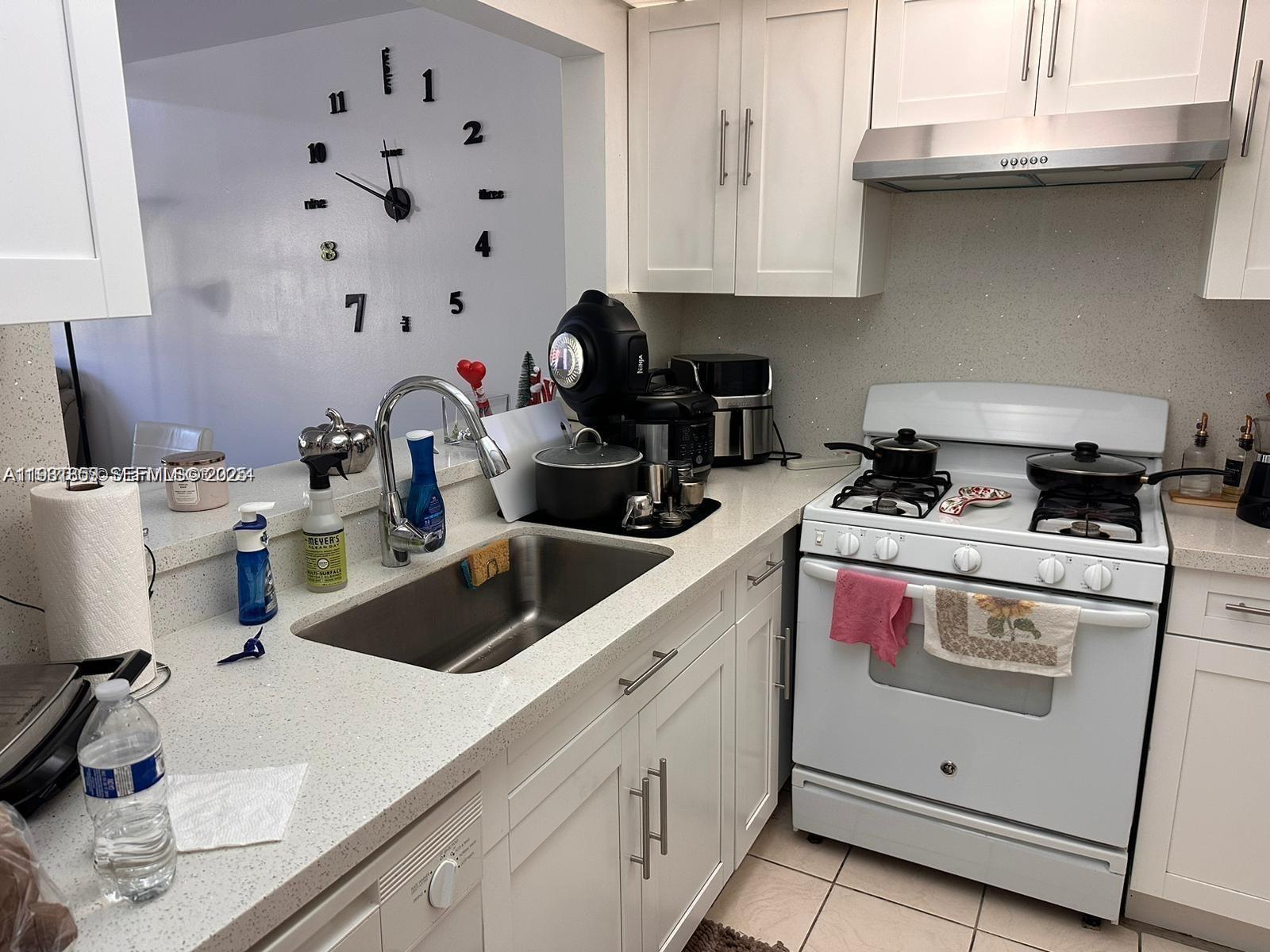 A kitchen features white cabinets, quartz countertops, a stainless steel sink, and a gas stove — 18101 NW 68th Ave # C202, Hialeah FL 33015, HIALEAH, FL