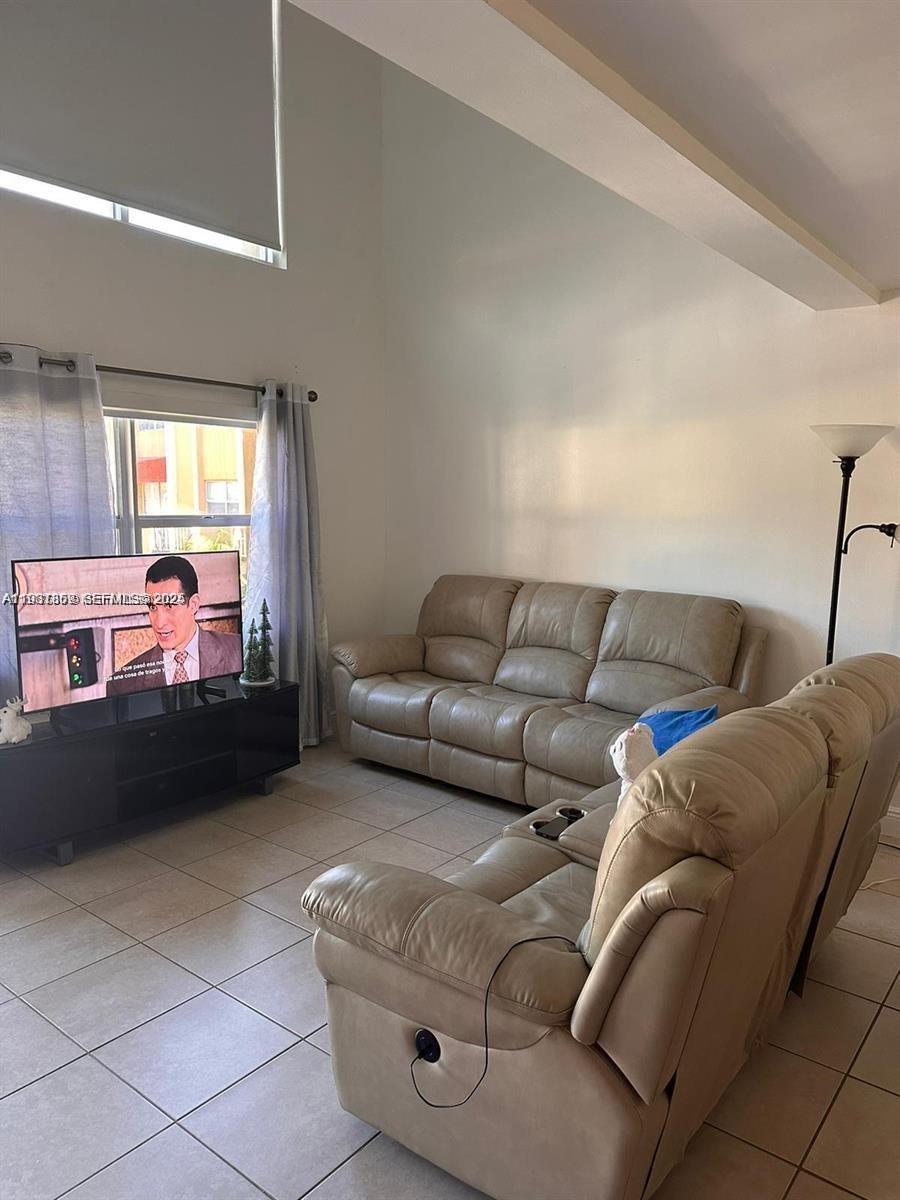 A living room features beige leather sofas, a television on a stand, and tiled floors — 18101 NW 68th Ave # C202, Hialeah FL 33015, HIALEAH, FL