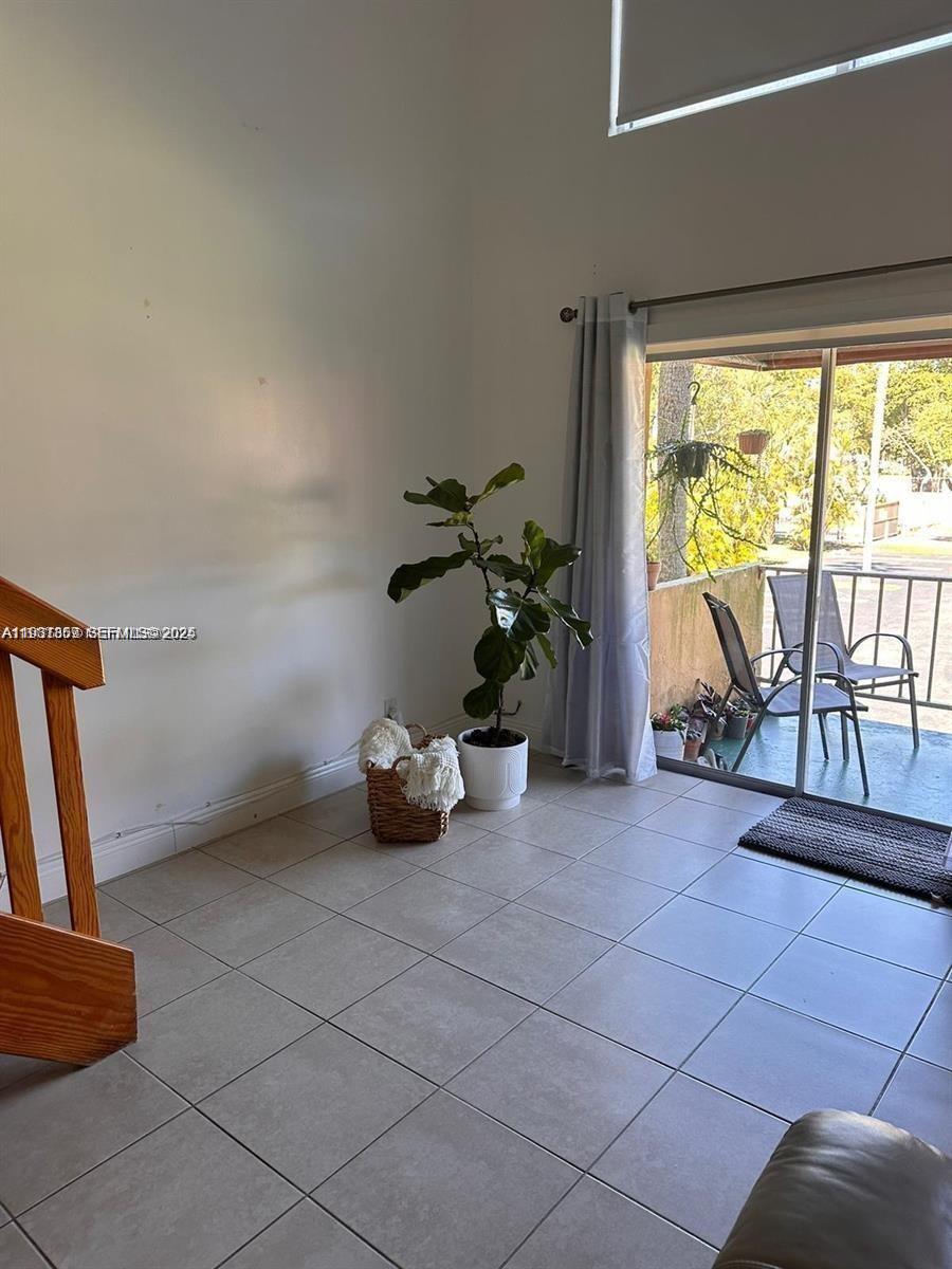 A living room features light tile floors, a fiddle leaf fig plant, and a balcony — 18101 NW 68th Ave # C202, Hialeah FL 33015, HIALEAH, FL