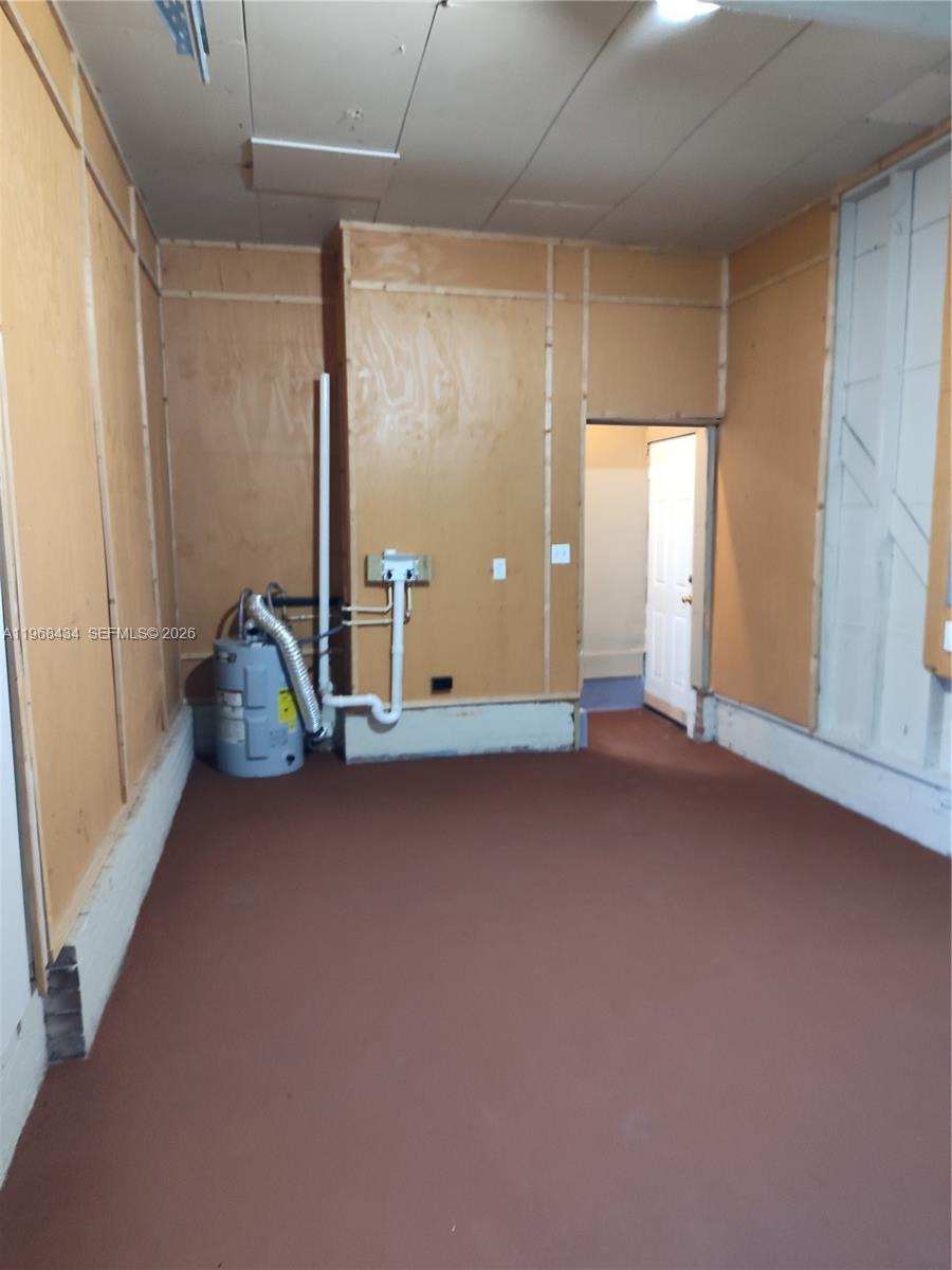 An unfinished utility room features plywood walls, a concrete floor, and a water heater — 1357 W 11TH, Jacksonville FL 32209, JACKSONVILLE, FL