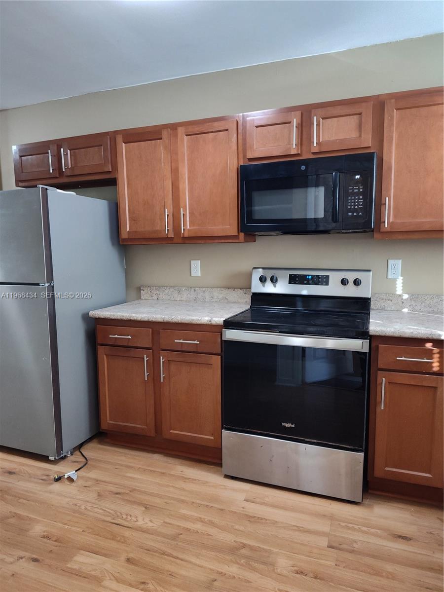 A kitchen features wood cabinets, stainless steel appliances, and light-colored countertops over wood-look flooring — 1357 W 11TH, Jacksonville FL 32209, JACKSONVILLE, FL