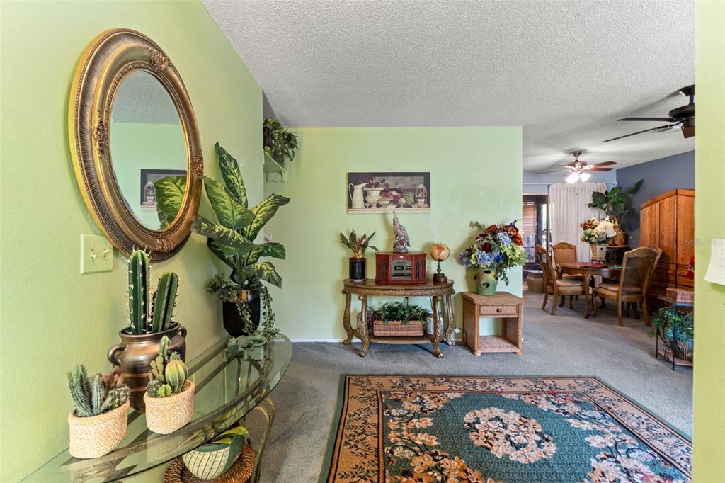 A living area with light green walls, a glass console table, and a dining room beyond — 10541 GREEN MEADOW LANE, PORT RICHEY, FL