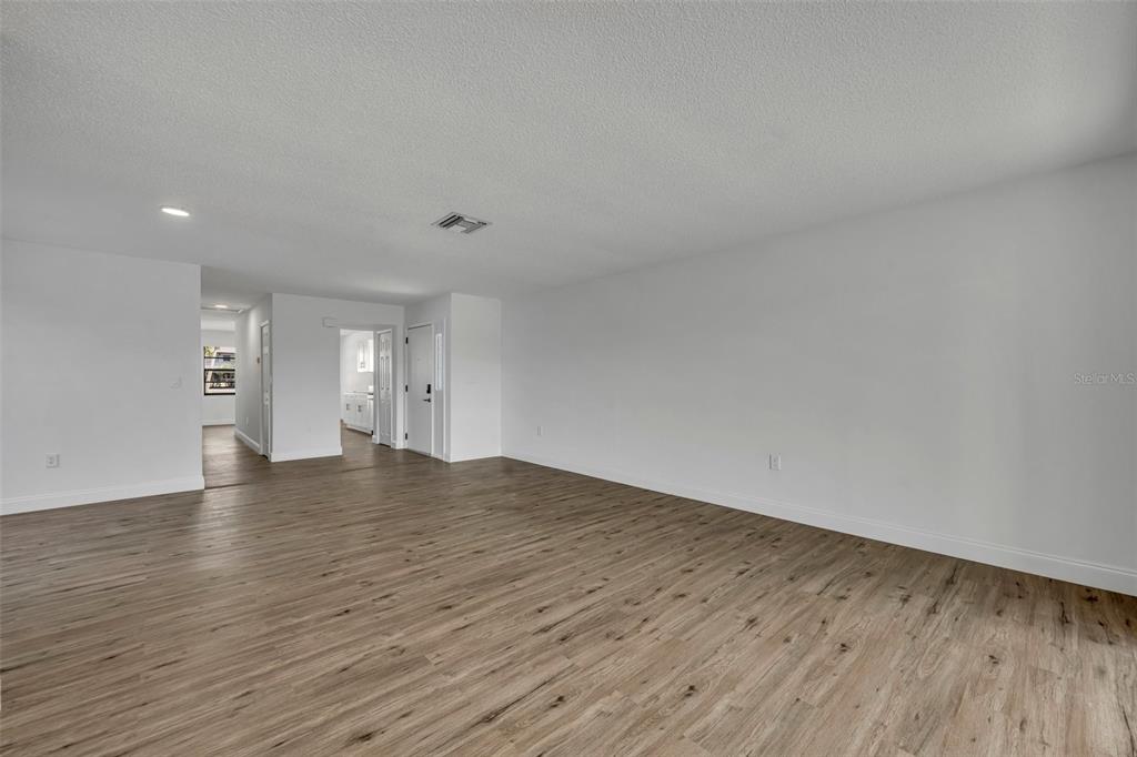 A living room features a brown sofa, two armchairs, a coffee table, and wood-look flooring — 4522 MARINE PARKWAY, NEW PORT RICHEY, FL