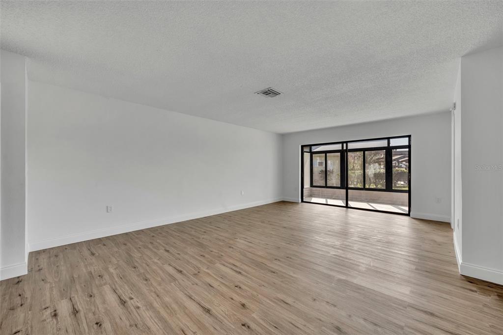 A living room with light wood floors, a leather sofa, and a wall-mounted television — 4522 MARINE PARKWAY, NEW PORT RICHEY, FL