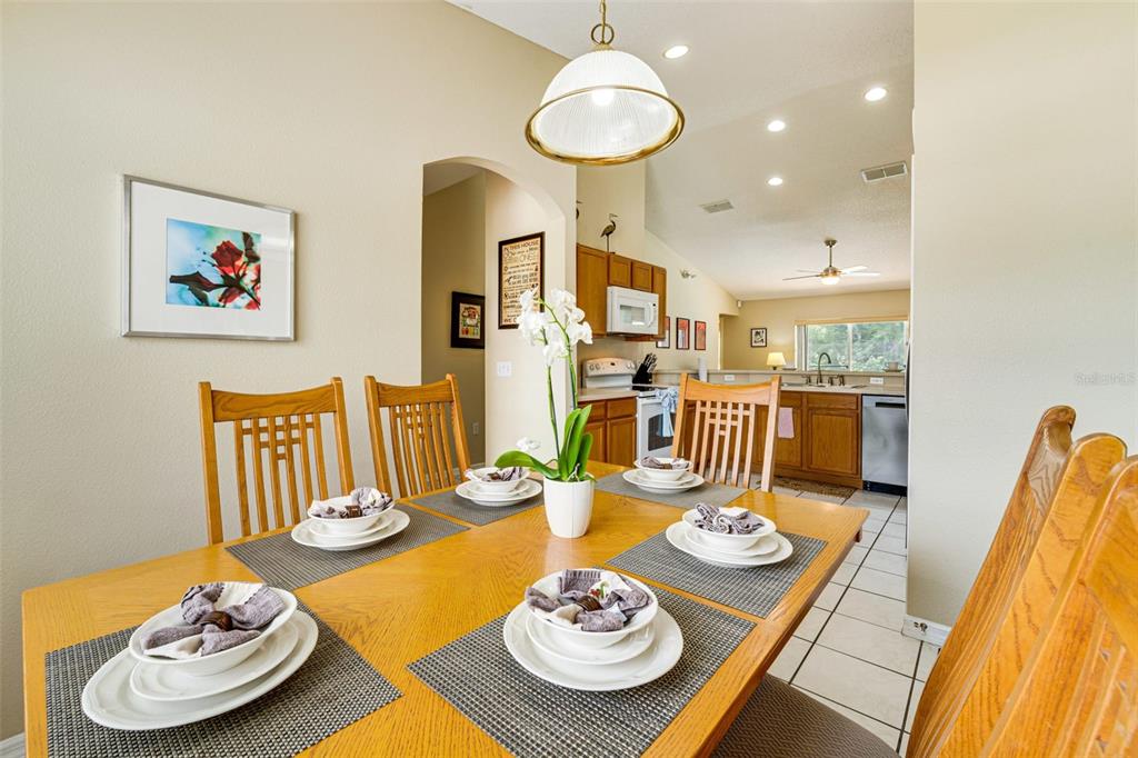A dining room with a wooden table and chairs leads into a kitchen with cabinets — 630 THOUSAND OAKS BOULEVARD, DAVENPORT, FL