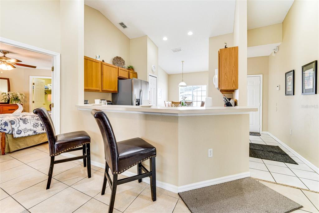 A kitchen with a breakfast bar, wooden cabinets, and tile flooring overlooks a dining area — 630 THOUSAND OAKS BOULEVARD, DAVENPORT, FL