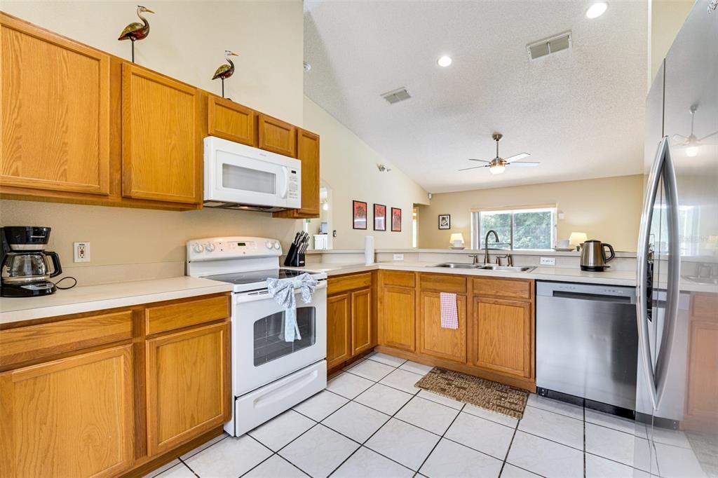 A kitchen with oak cabinets, white appliances, a tiled floor, and a vaulted ceiling — 630 THOUSAND OAKS BOULEVARD, DAVENPORT, FL