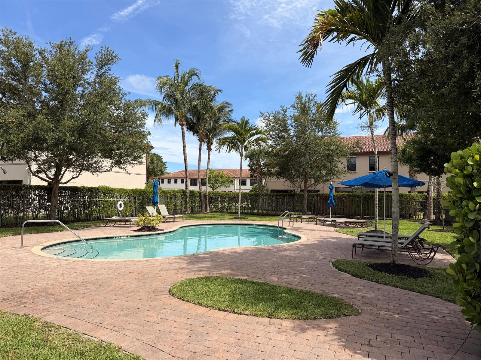 A swimming pool with lounge chairs and palm trees sits on a brick patio — 6145 Bangalow Drive, Lake Worth FL 33463, LAKE WORTH, FL