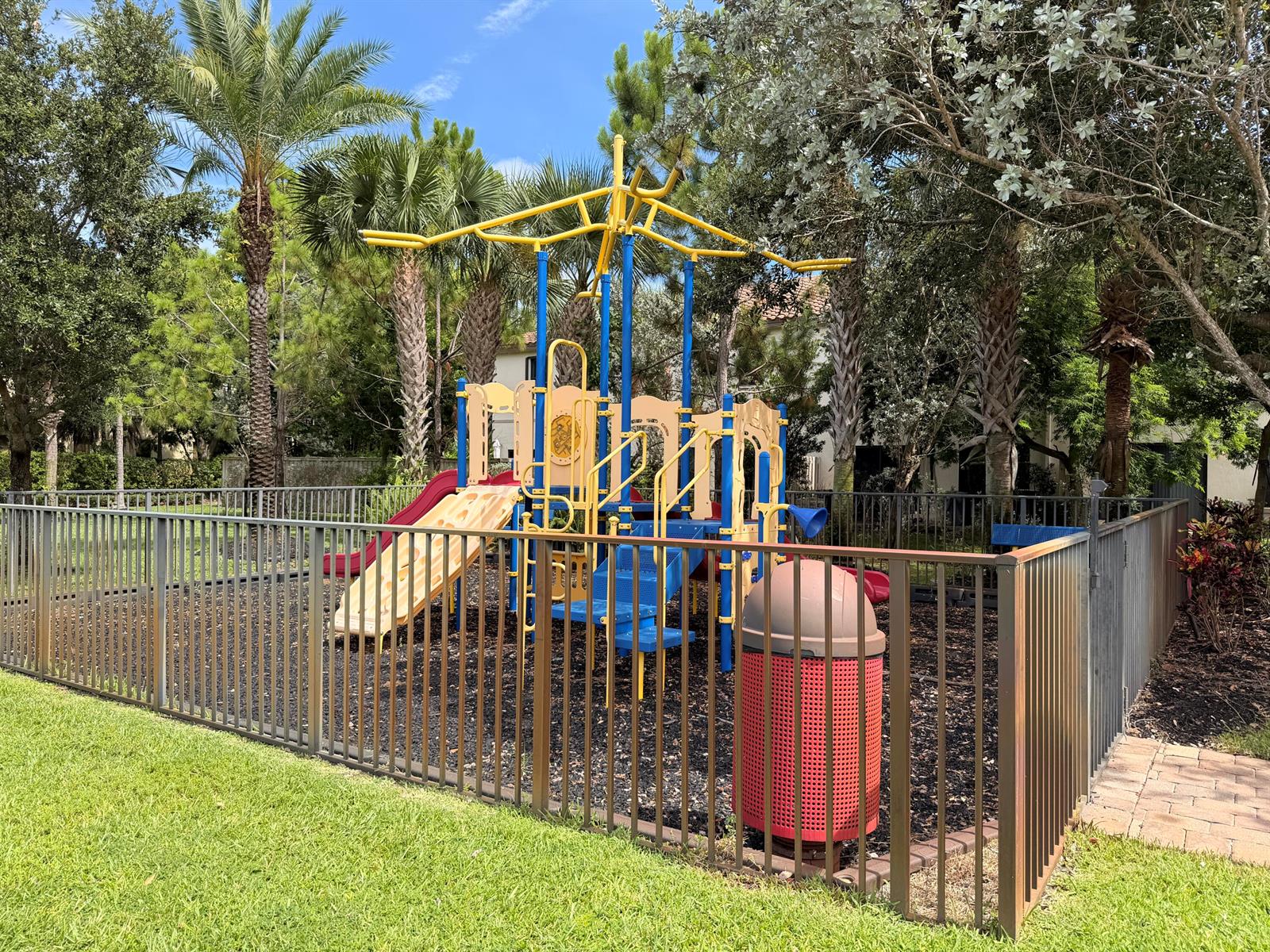 A fenced playground with a multi-level climbing structure and a red trash receptacle — 6145 Bangalow Drive, Lake Worth FL 33463, LAKE WORTH, FL