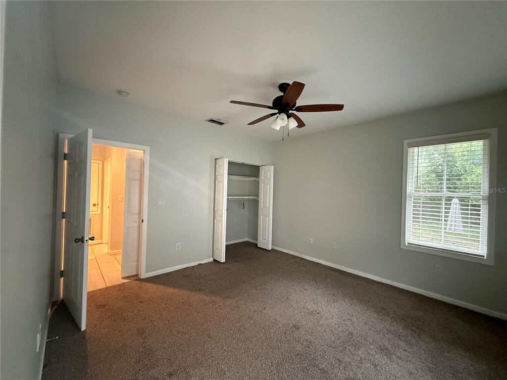 A bedroom features gray walls, brown carpet, a ceiling fan, a closet, and an attached bathroom — 325 W JEAN STREET, TAMPA, FL