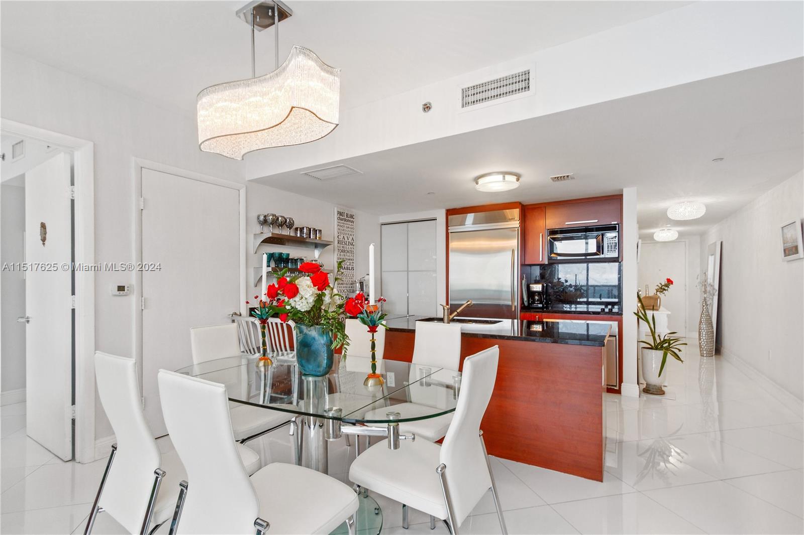 A dining area with a glass table and white chairs sits adjacent to a modern kitchen — 1830 S OCEAN DR, Hallandale Beach FL 33009, HALLANDALE BEACH, FL