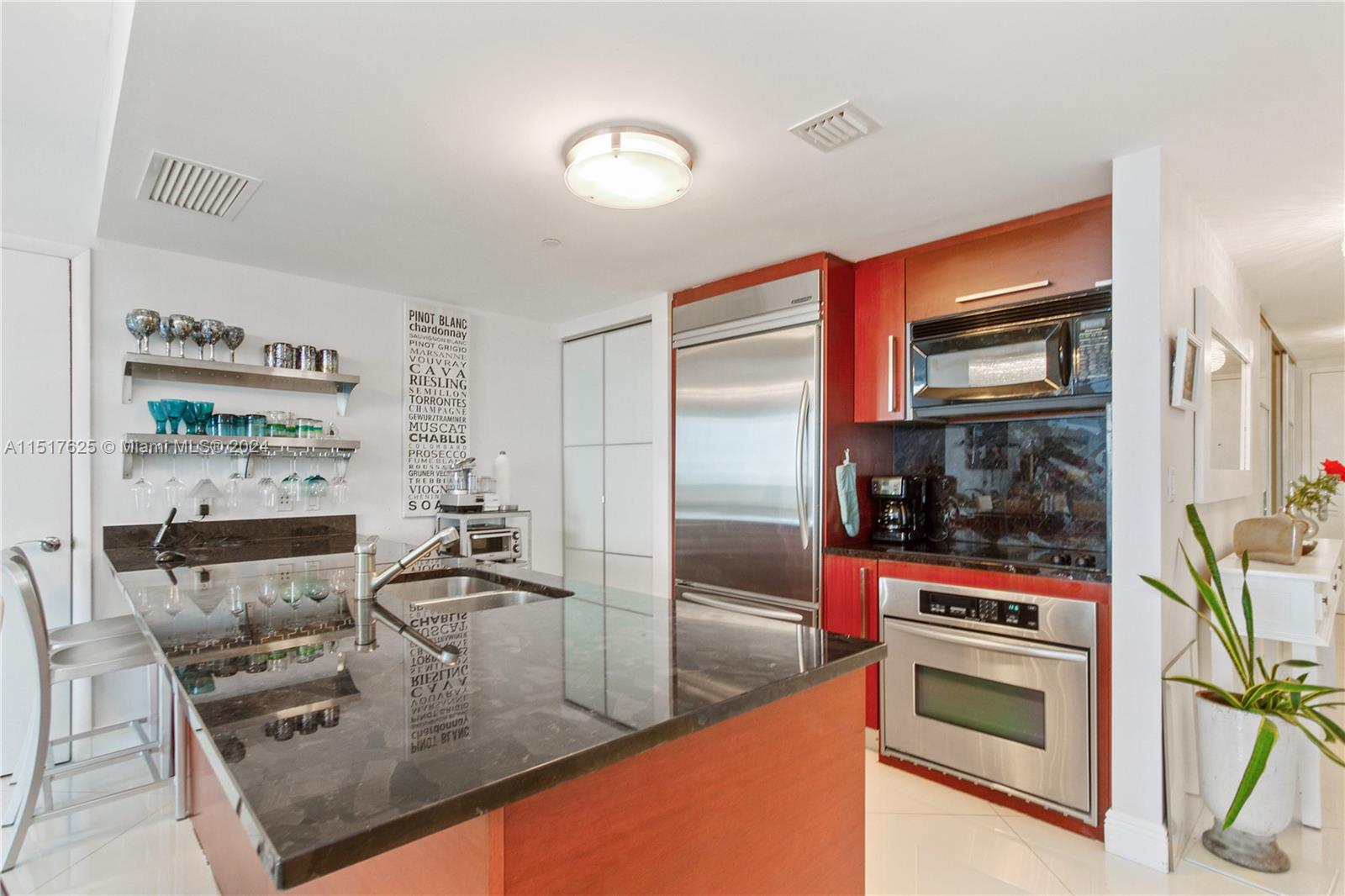 A modern kitchen features dark granite countertops, stainless steel appliances, and wood cabinetry — 1830 S OCEAN DR, Hallandale Beach FL 33009, HALLANDALE BEACH, FL