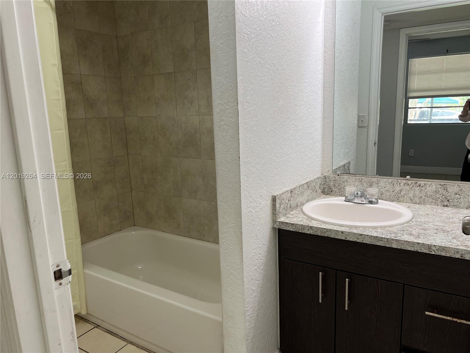 A bathroom features a tiled shower-tub combination next to a vanity with a stone countertop — 1237 SW 46th Ave # 801, Pompano Beach FL 33069, POMPANO BEACH, FL