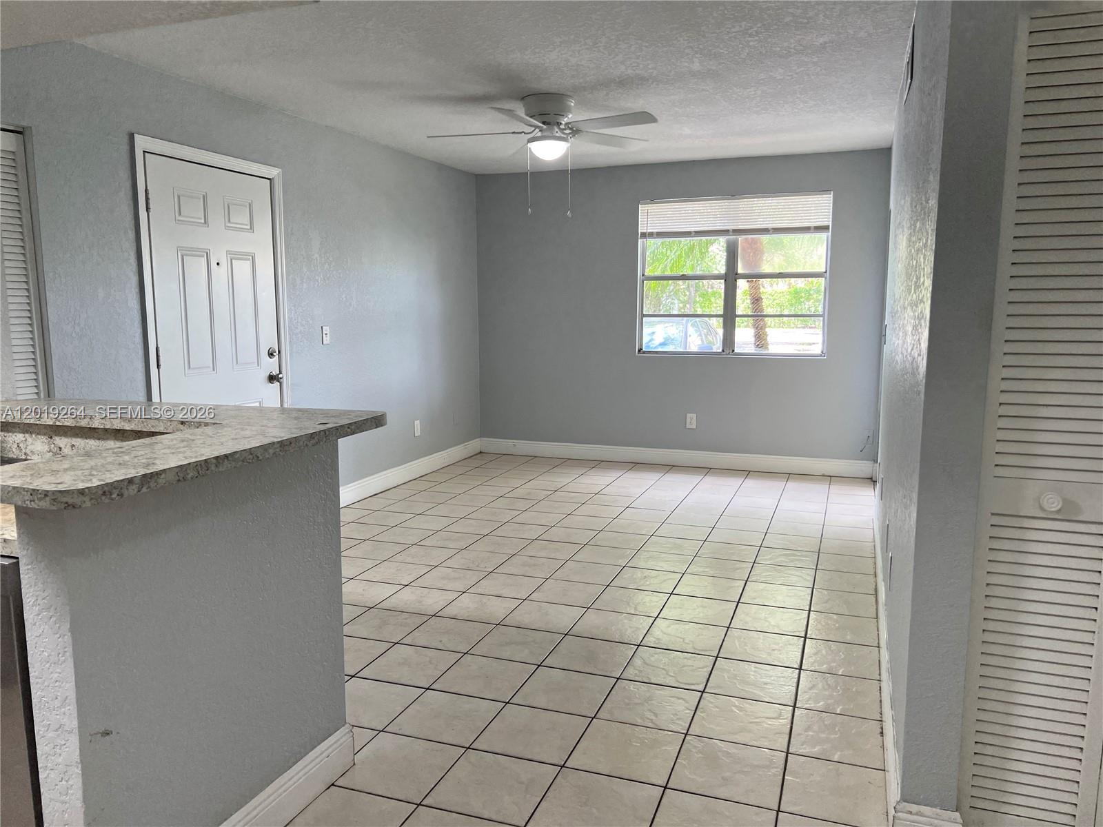 An empty room features light gray walls, white tile flooring, a ceiling fan, and a window — 1237 SW 46th Ave # 801, Pompano Beach FL 33069, POMPANO BEACH, FL