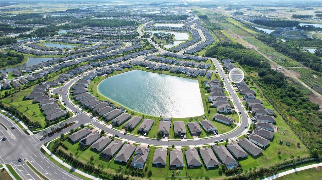 An aerial view shows a suburban neighborhood with houses surrounding a central lake — 11636 LITTLE RIVER WAY, PARRISH, FL
