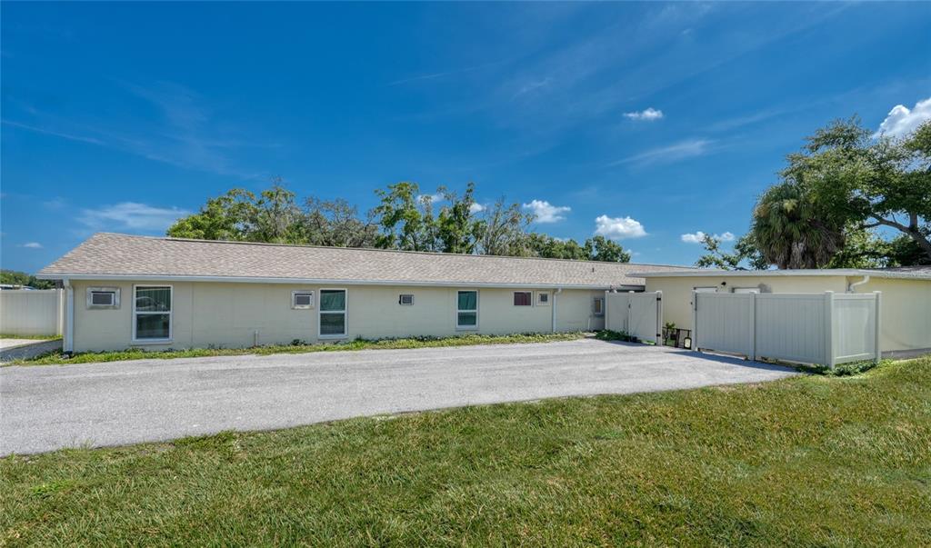 A long, single-story house with a light-colored exterior and a gravel driveway in front — 4615 N HESPERIDES STREET, TAMPA, FL
