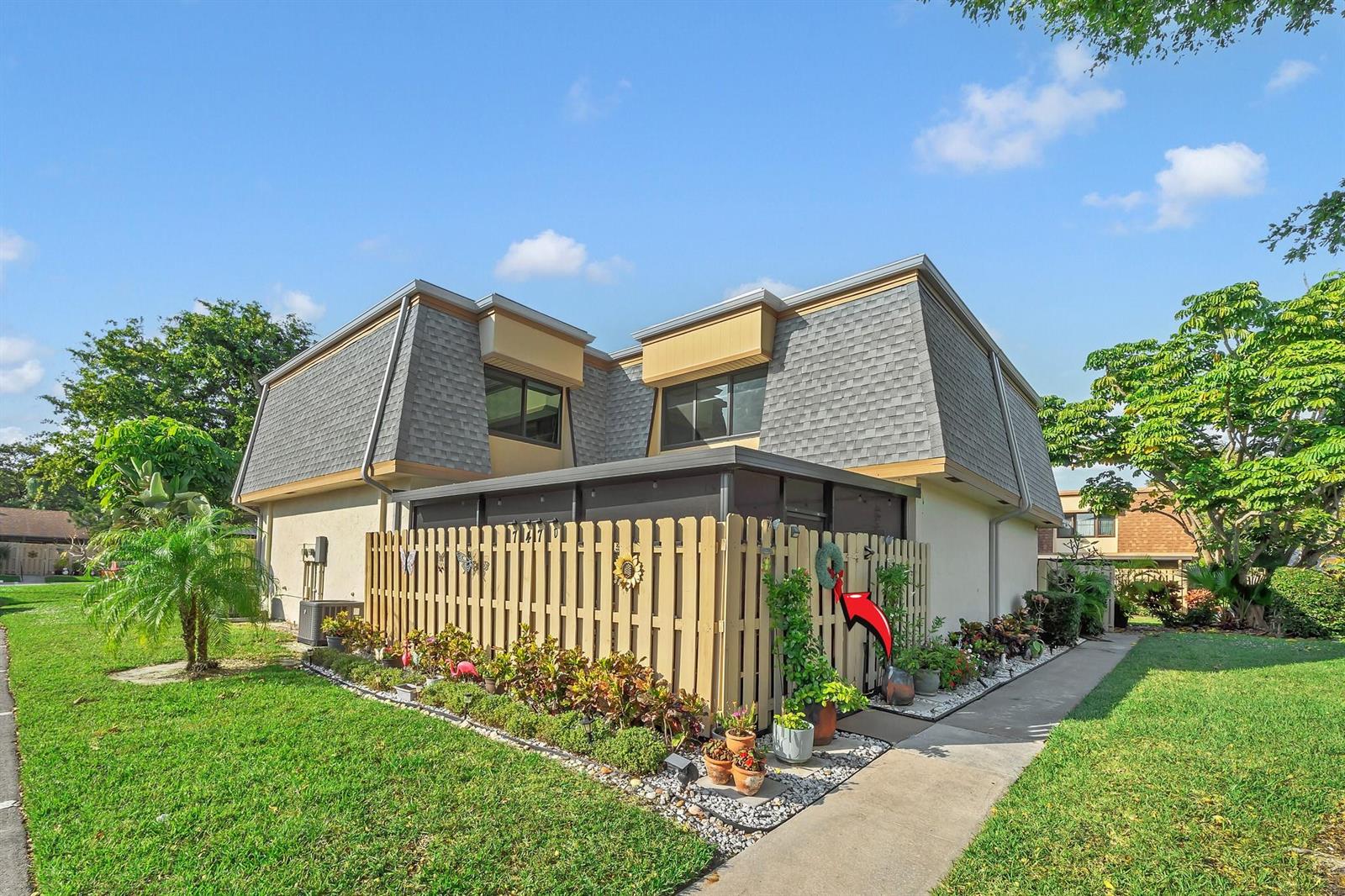 A two-story townhouse with a fenced patio, shingled mansard roof, and surrounding green lawn — 747 NW 30th Avenue # D, Delray Beach FL 33445, DELRAY BEACH, FL