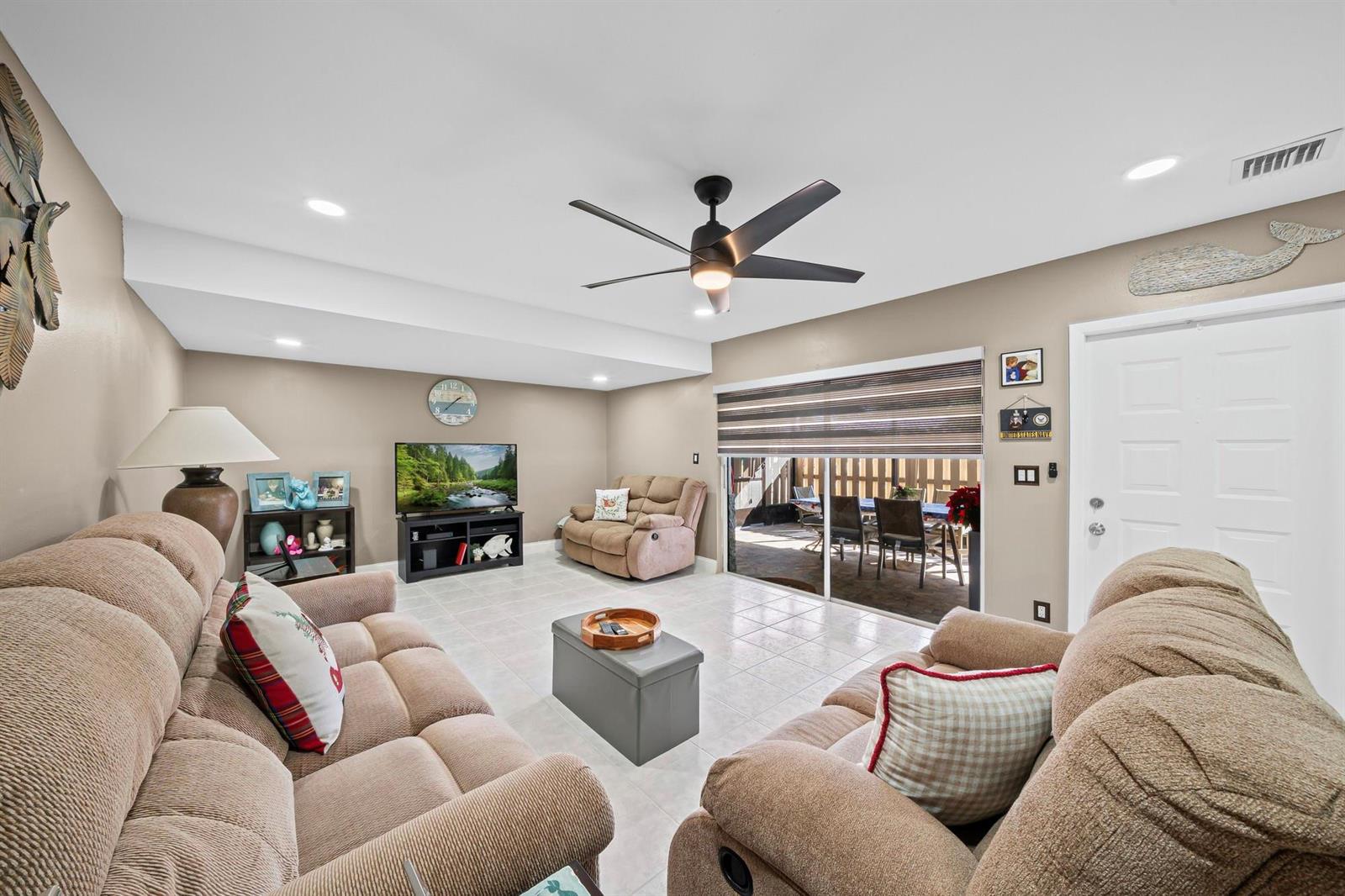 A living room features beige tile floors, two tan sofas, a ceiling fan, and sliding doors — 747 NW 30th Avenue # D, Delray Beach FL 33445, DELRAY BEACH, FL