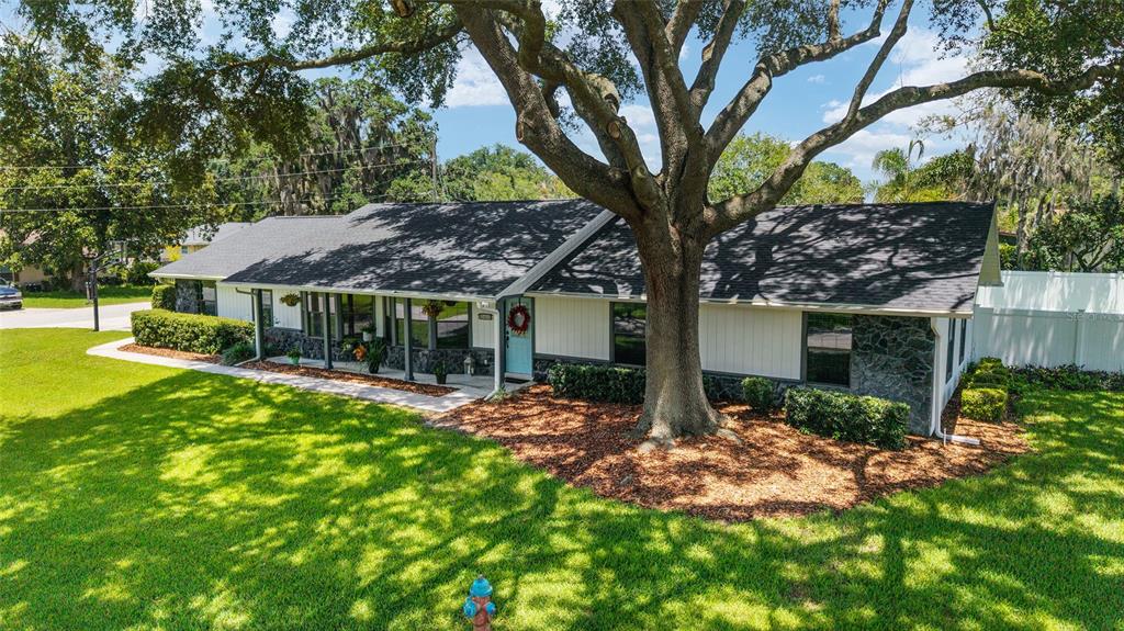 A single-story house with white siding, stone accents, and a large tree in the front yard — 3453 SE 25TH AVENUE, OCALA, FL
