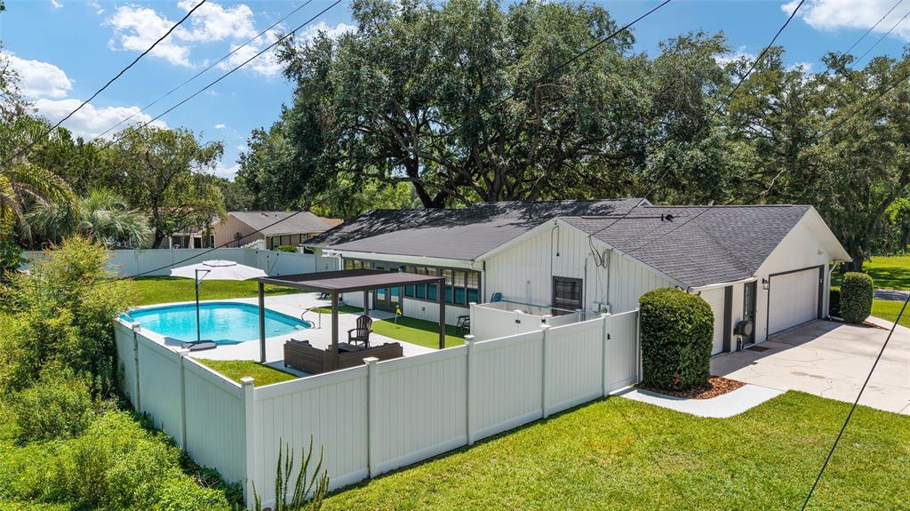An exterior view of a white house with a swimming pool and a fenced backyard — 3453 SE 25TH AVENUE, OCALA, FL