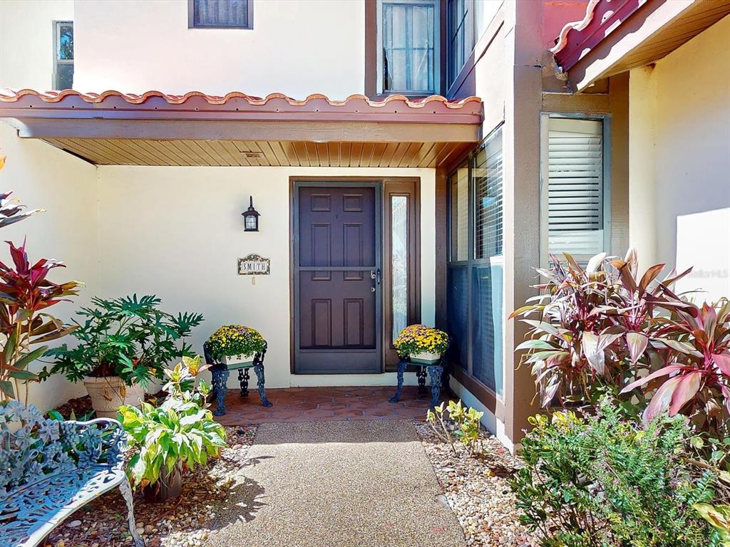A front entryway features a brown door, a tiled porch, and potted plants — 109 COVENTRY LANE, HAINES CITY, FL