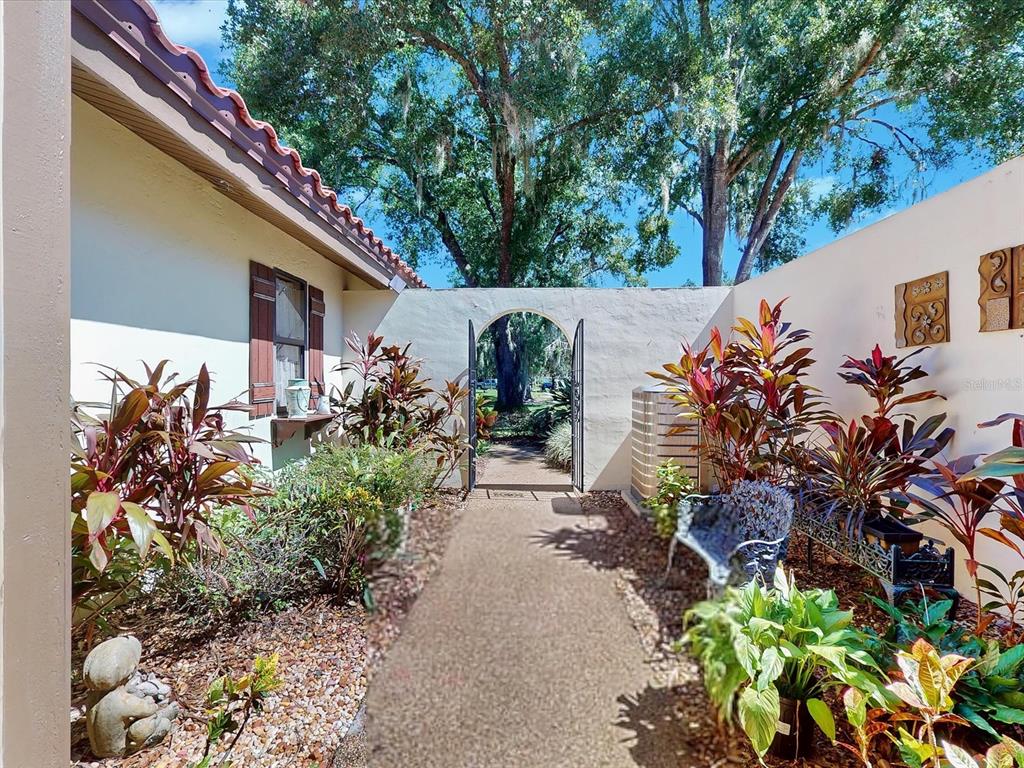 A paved walkway leads through a gated courtyard between a house and a stucco wall — 109 COVENTRY LANE, HAINES CITY, FL