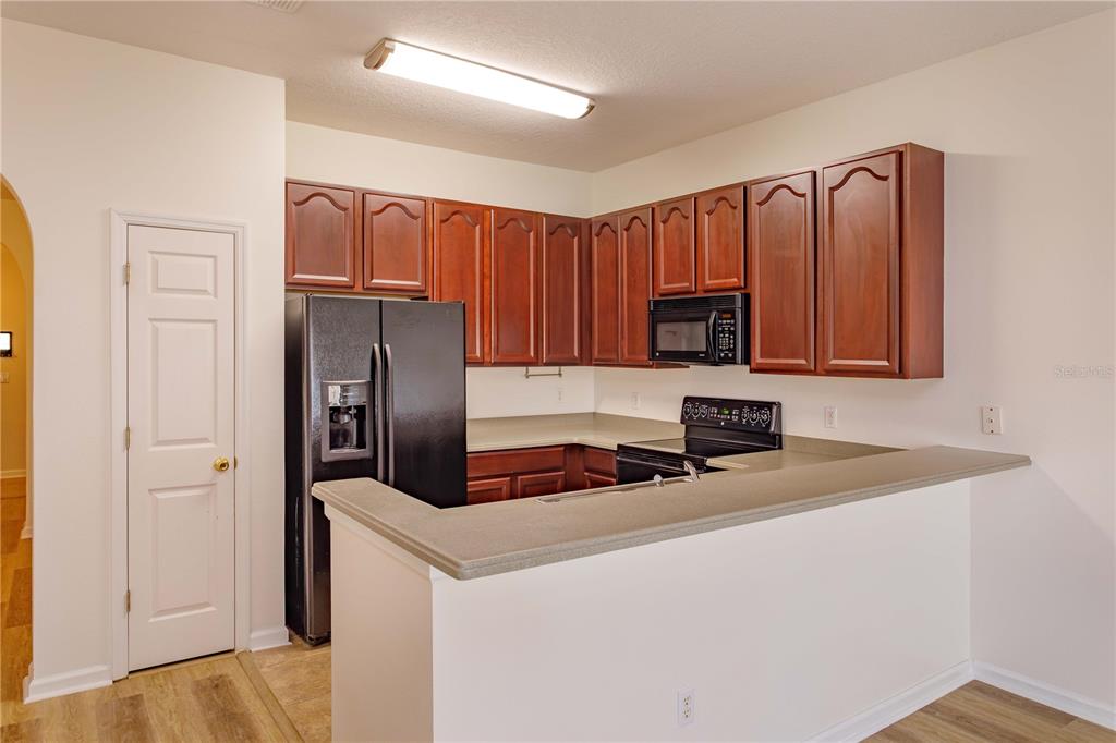 A kitchen features wood cabinets, black appliances, and a breakfast bar with a countertop — 16460 CEDAR CREST DRIVE, ORLANDO, FL