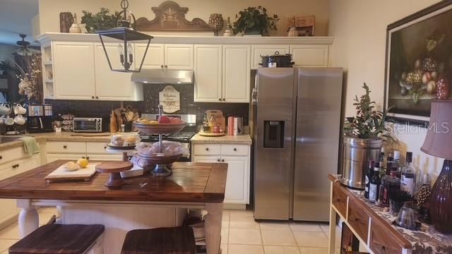 A kitchen features white cabinets, a wooden island, stainless steel appliances, and a side table — 30114 EMMETTS COURT, WESLEY CHAPEL, FL