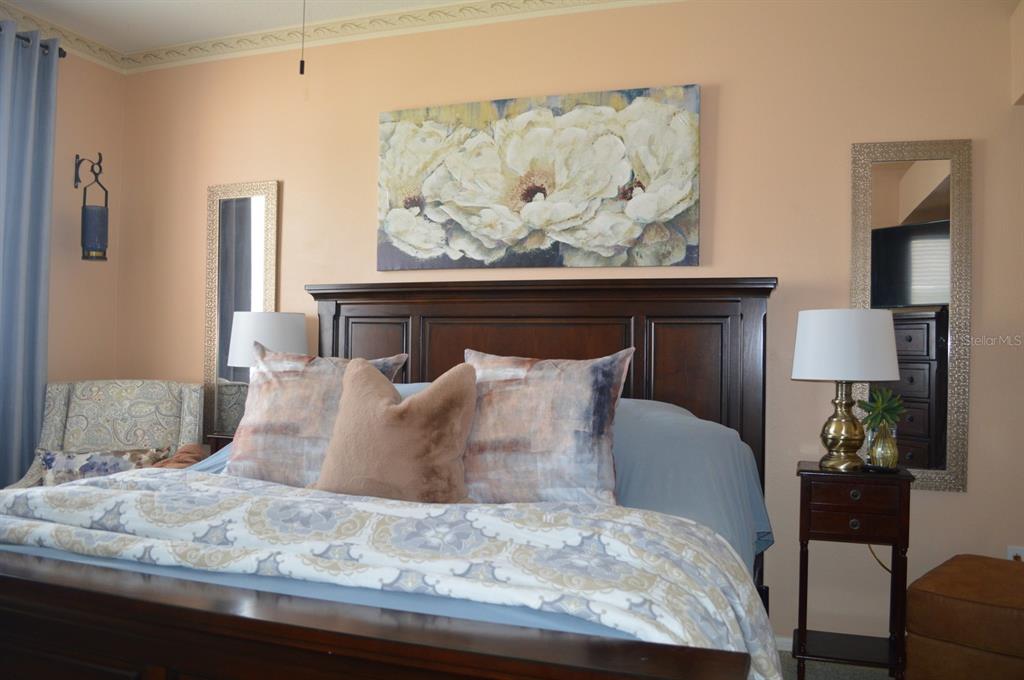 A bedroom features a dark wood headboard, floral wall art, and two mirrored wall accents — 30114 EMMETTS COURT, WESLEY CHAPEL, FL