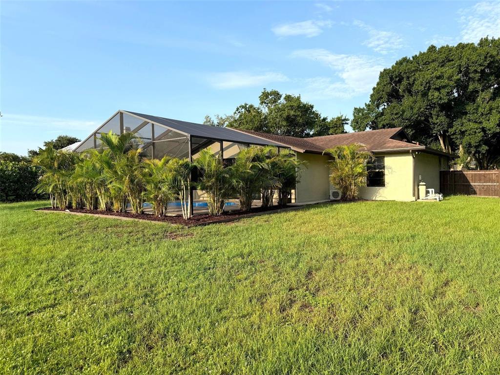 A house with a screened-in pool enclosure and palm trees sits on a grassy lawn — 1003 134TH STREET E, BRADENTON, FL